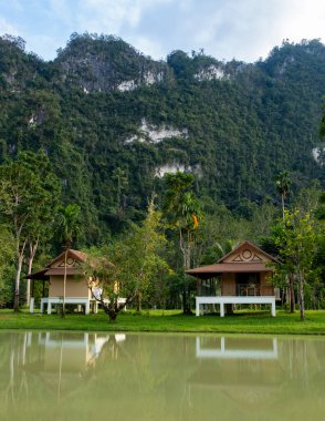 Khao Sok Tayland 'ın dingin güzelliğini sakin bir göletin kenarındaki büyüleyici bungalovlarla yaşayın. Etrafı yemyeşil tepeler ve canlı doğa ile çevrili bu dinlenmek için mükemmel bir dinlenme yeri..