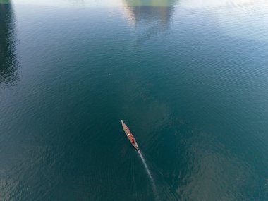 Tayland 'ın Khao Sok kentindeki Cheow Lan Gölü' nün huzurlu güzelliğini deneyimleyin. Orada yemyeşil dağlarla çevrili, ışıl ışıl sularda süzülen tek bir tekne var..
