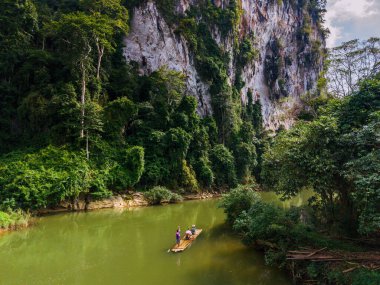 Huzurlu nehri ve dramatik kireçtaşı kayalıklarıyla Khao Sok Ulusal Parkı 'nın güzelliğini keşfedin. Bir çift, Tayland 'da ormanda bir bambu salında tatilde.