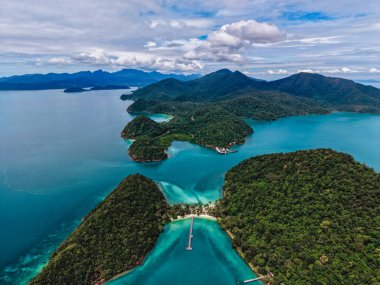 Koh Chang, Tayland 'daki Ko Ngam plajının çarpıcı hava manzarasını keşfedin. Canlı mavi sular, yeşil tepeler ve bulutlu bir gökyüzü altında huzurlu bir manzara..