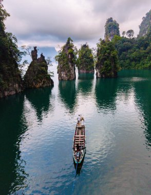 Yalnız bir tekne Cheow Lan Gölü 'nün sakin, zümrüt sularında süzülüyor. Etrafı çarpıcı kireçtaşı kayalıkları ve yemyeşil alanlarla çevrili. Khao Sok Tayland
