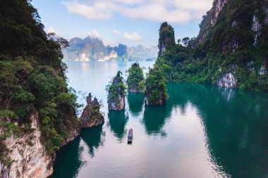 Khao Sok, Tayland 'daki Cheow Lan Gölü' nün dingin güzelliğini keşfedin. Berrak sulardan yükselen yemyeşil kayalıklar huzurlu bir tekne yolculuğu için sakin bir zemin oluşturuyor..