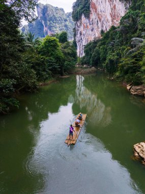 Tayland, Khao Sok 'un sakin sularında maceracılar bir bambu salında süzülürken.