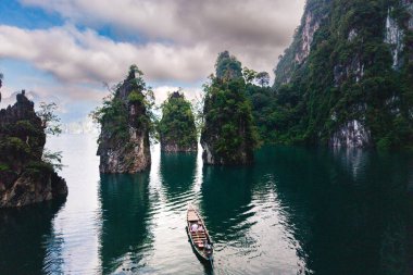 Cheow Lan Gölü 'ndeki sakin sularda, görkemli kireçtaşı kayalıkları ve yemyeşil yamaçlarla çevrili. Khao Sok Tayland