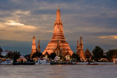 Şafak Tapınağı olarak bilinen Wat Arun, Alacakaranlıkta Bangkok 'taki Chao Phraya Nehri' nin yanında güzel bir şekilde parlar. Ziyaretçiler suya yansıyan çarpıcı mimariye hayran..