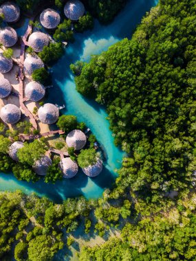 Tayland 'daki Koh Phayam Adası' nın canlı yeşilliğine yerleşmiş büyüleyici bungalovlar sakin suları kaplıyor. Otel ve mangrov ağaçları olan bir nehir.