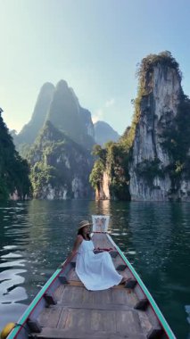 Tayland 'daki Khao Sok Ulusal Parkı' nın çarpıcı manzaralarını görün. Zümrüt sularında süzülen huzurlu bir tekne kayalıkları, verimli kayalıklar ve görkemli dağlarla çevrili..