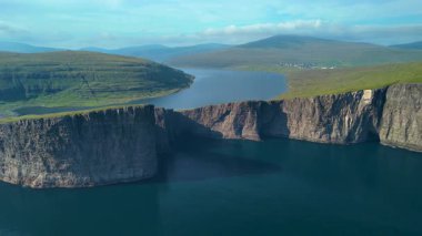 Faroe Adaları 'ndaki Sorvagsvatn Gölü etrafındaki manzaraya çarpıcı kayalıklar hakim. Sakin su, etrafındaki tepelerin ve gökyüzünün güzelliğini yansıtıyor ve nefes kesici bir manzara yaratıyor..