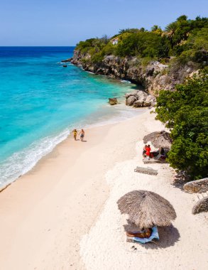 Ziyaretçiler, Curacao 'nun Westpunt kentindeki Playa Kalki Sahili' nin el değmemiş kumları boyunca yürüyüp güneşin altında güneşleniyorlar. Bereketli yeşillik gölgeyi sağlar. Turkuaz sular ise rahatlamayı davet eder..