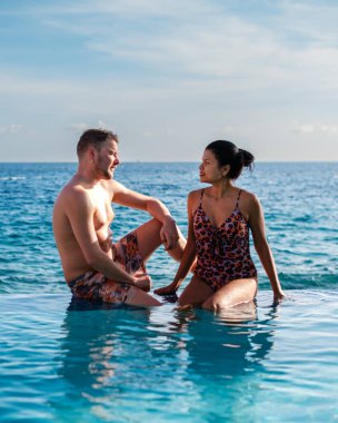 Bir çift, Curacao 'daki Willemstad' ın berrak mavi sularına bakan sonsuz bir havuzda sakin bir öğleden sonranın tadını çıkarıyor. Romantik bir kaçamak ve unutulmaz tatil anıları için mükemmel bir yer..