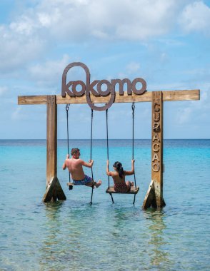 Curacao 'daki Kokomo Sahili' nde salıncakların keyfini çıkaran bir çift, çarpıcı turkuaz sular ve canlı bir gökyüzü ile çevrili. Karayip güneşinin altında rahatlamak ve eğlenmek için mükemmel bir kaçış..