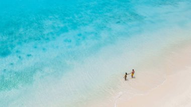 Klein Curacao 'nun el ele tutuşmuş beyaz kumları boyunca kristal berrak sularla çevrili birkaç gezinti. Curacao sahilinde yürüyen bir çift kadın ve erkeğin robot görüntüsü.