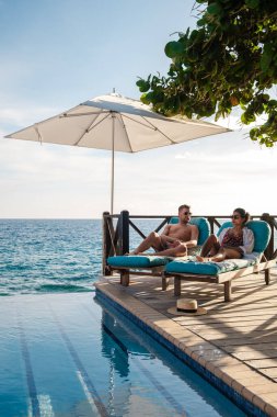 Bir çift, Willemstad, Curacao 'daki okyanusun kıyısında güneşlenmenin tadını çıkarıyor. Curacao 'da tatilde olan birkaç erkek ve kadın havuz kenarında dinleniyorlar.