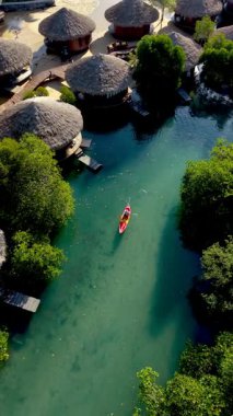 Tayland, Koh Phayam 'ın sakin sularında, yemyeşil mangrovlar ve sıcacık sazdan kulübelerle çevrili, ada yaşamının ve doğal güzelliğin özünü yakalayarak kürek çekin..
