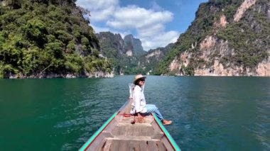 Bir gezgin olarak Khao Sok Tayland 'ın sükunetini yaşayın uzun kuyruklu bir teknede huzurlu bir anın tadını çıkarın. yemyeşil dağlar ve gök mavisi sular macera için çarpıcı bir zemin oluşturur..