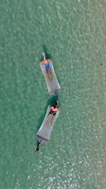 İki insan hamaklarda huzurlu bir anın tadını çıkarıyorlar. Tayland 'ın Koh Kood Adası' nın berrak sularında nazikçe sallanıyorlar. Güneş ışığı yüzeyde parıldıyor, sakin bir kaçış yaratıyor..