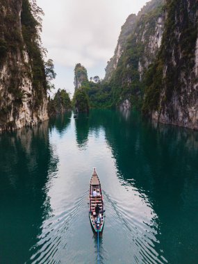Geleneksel bir tekne zümrüt sularda süzülürken görkemli kireçtaşı kayalıklarıyla çevrili Cheow Lan Gölü 'nün sakinliğini keşfedin. Khao Sok, Tayland