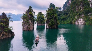 Tayland 'ın Khao Sok kentindeki Khao Lan Gölü' nün sakin sularını deneyin. Yüksek kireçtaşı kayalıkları ve yemyeşil alanlarla çevrili. Geleneksel bir tekne büyüleyici manzarada süzülür..