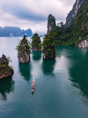 Khao Sok, Tayland 'daki Cheow Lan Gölü' nün sakin cazibesini deneyin. Turkuaz sulardan yükselen görkemli kireçtaşı kayalıkları keşif ve macera için mükemmel nefes kesici bir manzara yaratıyor..