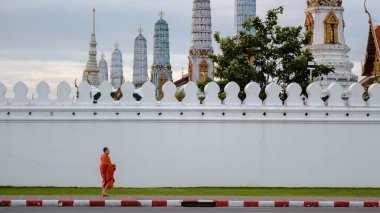 Bangkok, Tayland, 19 Kasım 2025 'te bir keşişin büyüleyici Wat Phra Kaew' ın yanından zarif bir şekilde geçişi ile sakin bir manzara gözler önüne serildi. Tarihi tapınak, sakin gökyüzüne karşı karmaşık mimarisini sergiliyor..