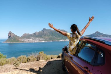 Chapman 's Peak Drive Cape Peninsula' da güneşli ve güneşli bir öğleden sonra Cape Town yakınlarında. Cape Town, araba yolculuğunda elleri havada bir kadın, kiralık arabada mutlu bir kadın.