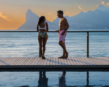 İki gezgin rıhtımın yanında dururken gün batımının keyfini çıkarıyorlar. Turuncu ve sarıların canlı renkleri havuzun sakin sularından yansıyarak Cape Town 'da romantik bir atmosfer yaratıyor..