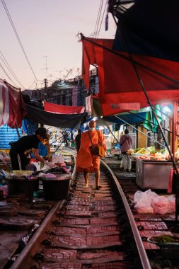 5 Aralık 2025 'te, Tayland' daki Maeklong Demiryolu Pazarı 'nda bir keşiş gün doğumunda pazar yolunda yürür ve bağış toplar.