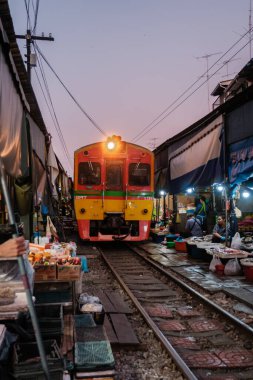 Tayland 'daki Maeklong Demiryolu Pazarı, 5 Aralık 2025, satıcıların tren yaklaşırken taze mallar sergilediği, günlük yaşam ve heyecanı harmanladığı yer.