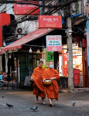 Bangkok, Tayland, 19 Kasım 2025, Çin Mahallesi 'nin parlak turuncu cübbeleriyle süslenmiş iki keşiş zarif bir şekilde yürüyorlar..