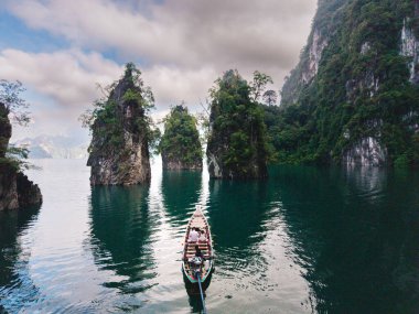 Khao Sok, Tayland 'daki Cheow Lan Gölü' nün dinginliğini hissedin. Sakin turkuaz sulardan yükselen kireçtaşı kayalıkları görkemli bir şekilde yükseliyor..