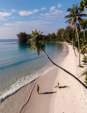 Tayland 'ın Koh Kood kentindeki Khlong Hin Sahili' nin güzelliğini keşfedin. Yumuşak beyaz kumların berrak sularla buluştuğu yer. Bir çift sallanan palmiye ağaçlarının altında rahatlar ve huzurlu bir kaçamağın tadını çıkarırlar..