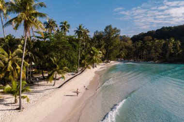 Koh Kood 'daki Khlong Hin Sahili yumuşak kumlu kıyıları, sallanan palmiyeleri ve kristal berrak sularıyla cennetin özünü yakalar. Koh Kood, Tayland 'da tatilde olan birkaç erkek ve kadın.