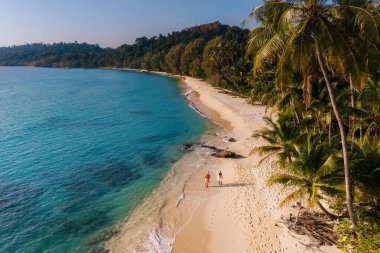 İki gezgin el ele geziyorlar Takhian Sahili 'nin el değmemiş kumları boyunca, Koh Kood, Tayland, güneşin altında güneşlenerek ve hafif dalgaların sesleriyle. Tropikal bir cennet bekliyor..
