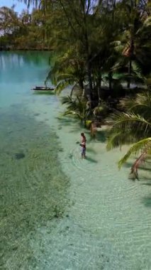 Koh Kood, Tayland 'ın nefes kesici güzelliğini tecrübe edin. Kristal berrak suların kumlu kıyılarla buluştuğu yer. Turkuaz renkli okyanusta yürüyen bir çift kadın ve erkek.