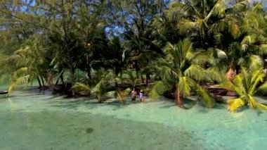 Tayland, Koh Kood 'un nefes kesici güzelliğini tecrübe edin, yumuşak dalgaların kıyıları okşadığı ve sallanan palmiyelerin rahatlamaya davet ettiği. Turkuaz renkli okyanusta bir çift kadın ve erkek.