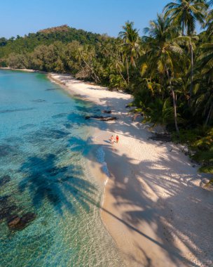 Bir çift Koh Kood, Tayland 'daki Takhian Sahili' nde huzurlu bir günün tadını çıkarıyor. Altın kumlar ve turkuaz sular, bereketli palmiyelerle çevrili gevşeme ve keşif için cennet gibi bir zemin oluşturur..