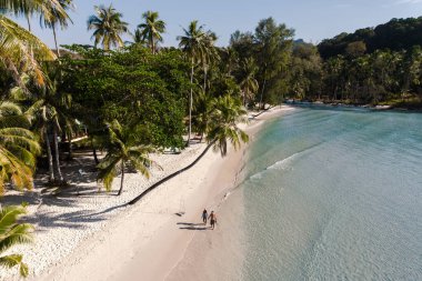 Bir çift, güzel Koh Kood, Tayland 'daki gür palmiye ağaçları ve kristal berrak sularla çevrili Khlong Hin' in yumuşak kumlu sahillerinde el ele yürür..