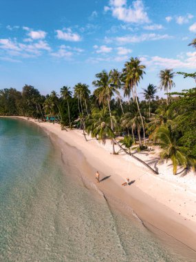 İki gezgin, Khlong Hin Sahili 'nin yumuşak kumlu sahillerinde, sallanan palmiye ağaçları ve Koh Kood Tayland' ın berrak turkuaz sularıyla çevrili bir şekilde yürürken, mükemmel bir tatil havası yaratıyor..