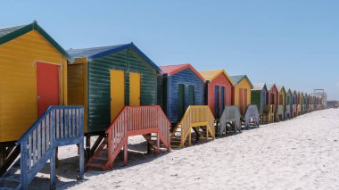 Parlak renkli plaj kulübeleri Muizenberg plajı boyunca gururla durur. Cape Town Güney Afrika
