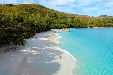 Praslin, Seyşeller 'deki Anse Lazio plajında iki gezgin el değmemiş kumsalda yürüyor. Bereketli yeşil tepeler ve kristal berraklığında turkuaz sularla çevrili burası rahatlamak için mükemmel bir kaçış yeri..