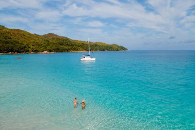 Çift, Anse Lazio plajında, çarpıcı turkuaz sular ve Seyşeller 'in yemyeşil yeşillikleriyle çevrili sakin bir anın tadını çıkarıyor. Romantik bir kaçamak ya da rahatlatıcı bir tatil için mükemmel.