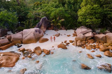 Praslin Seyşeller 'deki Grand Anse Sahili' nde huzurlu bir an yaşanıyor. Çift, yemyeşil yemyeşil ve parıldayan deniz tarafından vurucu kaya oluşumlarıyla çevrili yumuşak kumlarda yan yana durur..