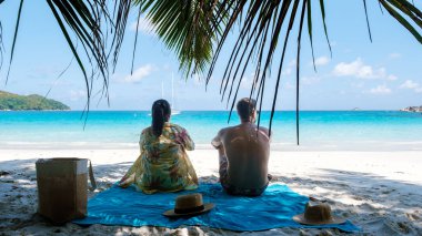 Seyşeller 'deki Praslin Adası' ndaki Anse Georgette 'de sakin bir günün tadını çıkarın. İki arkadaş sallanan palmiye ağaçlarının altındaki yumuşak kumda dinlenir, güneşi emer ve nefes kesici turkuaz dalgalar solur..