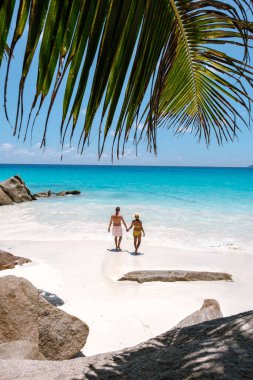 Bir çift Praslin Seyşeller 'de Anse Georgette' in yumuşak beyaz kumunda el ele yürür. Parlak turkuaz sular, yemyeşil sularla çevrili sıcak güneşin altında yavaşça ayaklarının altında dolaşırlar..