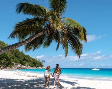 İki aşık el ele yürür Anse Georgette 'in el değmemiş kumlarında, canlı yeşillikler ve turkuaz sularla çevrili, güneşli Seyşeller gökyüzünün altında huzurlu bir anın tadını çıkarırlar..