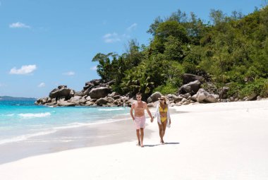 Çift, gök suları ve yemyeşil yeşilliklerle çevrili Anse Georgette 'in beyaz kumlu plajı boyunca romantik bir yürüyüş yapıyor. Praslin, Seyşeller