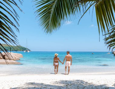 Çift, Anse Georgette 'in turkuaz sular ve yemyeşil sularla çevrili yumuşak beyaz kumları boyunca el ele yürür. Praslin Seyşeller 'de romantizm ve rahatlama için mükemmel bir tatil yeri.