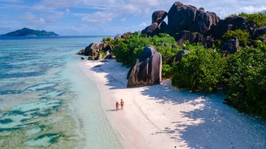 Bir çift, Anse Source d 'Argent' ın sakin kıyılarında dolaşır, yumuşak beyaz kumların kristal berrak sularla buluştuğu yerde. Benzersiz kaya oluşumları resim gibi bir cennet yaratır. La Digue, Seyşeller