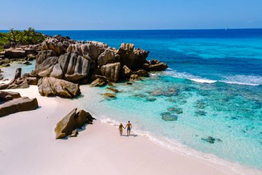 İki gezgin, Anse Cocos sahilinin el değmemiş kumları boyunca yüksek kayalar ve canlı turkuaz sularla çevrili huzurlu bir yürüyüşün tadını çıkarıyorlar. Mükemmel bir tropikal kaçış bekliyor. La Digue Seyşeller