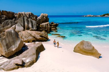 La Digue, Seyşeller 'deki Anse Cocos plajlarını keşfedin. Kumsalda yürüyen bir çift erkek ve kadın, insansız hava aracı görüntüsü.